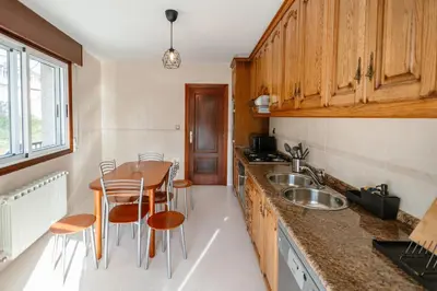a kitchen with wooden cabinets and a table and chairs at Casa Bella Lalin- 4 Double bedroom Galician Country Home! in Pontevedra