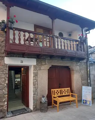 a wooden bench sitting outside of a building with a balcony at Hotel Rural Virgen del Carmen in Molinaseca