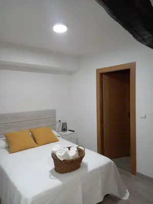 a bedroom with a white bed with a basket on it at Hotel Rural Virgen del Carmen in Molinaseca
