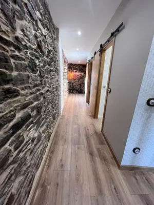 a hallway with a stone wall and a mirror at El Rincón del Val in Priaranza del Bierzo