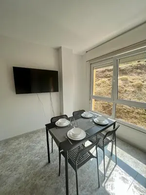 a dining room with a table with chairs and a television at RAXEL - MIÑO in Miño