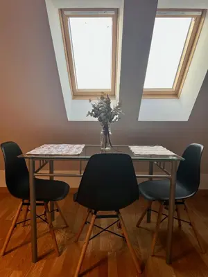 a dining room table with four chairs and a vase with flowers at Ático Camino Santiago: El Comienzo Perfecto in Sarria