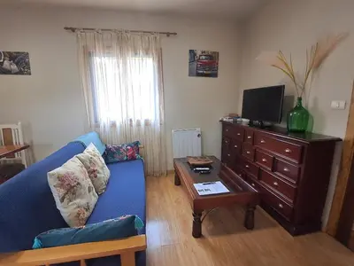 a living room with a blue couch and a tv at FOGAR CAÑÓN DO SIL - En la Ribeira Sacra in Nogueira de Ramuin