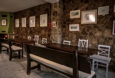 a room with two tables and chairs and a stone wall at Pensión Albergue A Pedra in Sarria