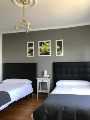 a bedroom with two beds and a side table at Pensión Albergue A Pedra in Sarria