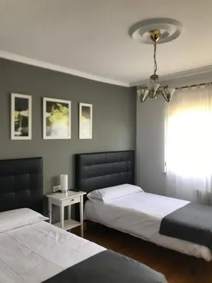a bedroom with two beds and a window at Pensión Albergue A Pedra in Sarria