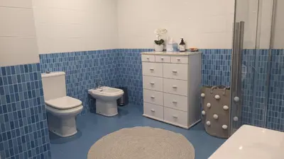 a blue tiled bathroom with a toilet and a sink at Apartamento Silleda Confort in Silleda