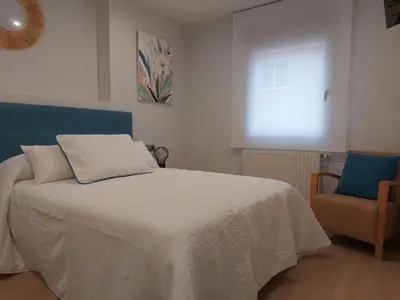 a bedroom with a bed and a chair and a window at Apartamento Silleda Confort in Silleda