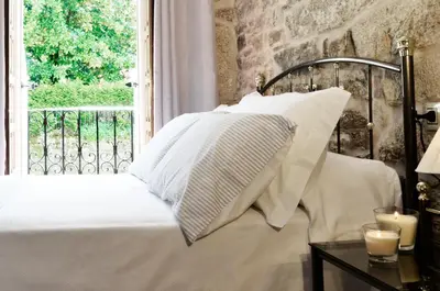 a bed with white sheets and pillows next to a window at Sete Artes by Como en Casa in Santiago de Compostela