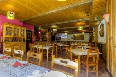 a restaurant with wooden floors and tables and chairs at Hostal Rural La Tintoreria in Villablino