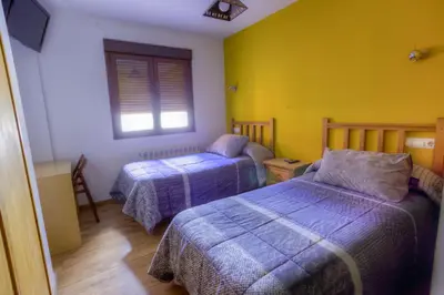 a bedroom with two beds and a window at Hostal Rural La Tintoreria in Villablino