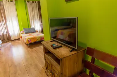 a living room with green walls and a flat screen tv at Hostal Rural La Tintoreria in Villablino