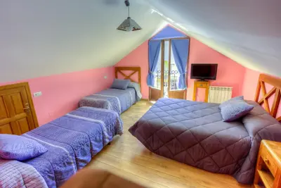 a living room with two beds and a couch at Hostal Rural La Tintoreria in Villablino