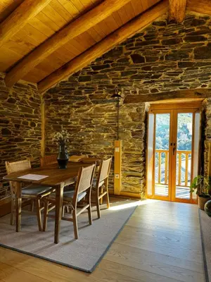 a dining room with a wooden table and chairs at Lar da cima in Folgoso