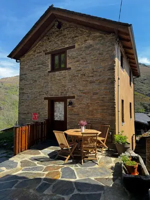 a patio with a table and chairs in front of a building at Lar da cima in Folgoso