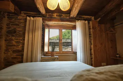 a bedroom with a large bed and a window at Lar da cima in Folgoso