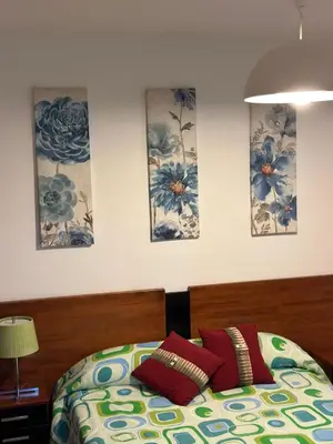 a bedroom with a bed with three paintings on the wall at Piso da Ulla in A Estrada