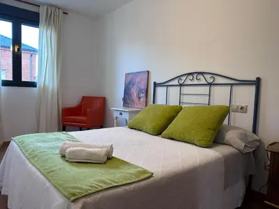 a bedroom with a bed with green pillows and a red chair at Suite Rigel in Ponferrada