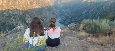 two women sitting on top of a mountain overlooking a river at Ás Portas do Sil - En la Ribeira Sacra in Villar de Cerreda
