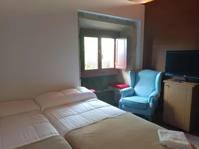 a bedroom with a bed and a chair and a television at Casa das Capelas in Villamarín