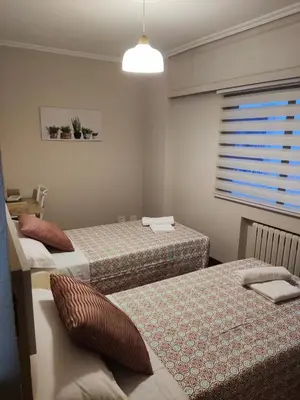 a bedroom with two beds and a window with a shutter at Casa andaina in Palas de Rei