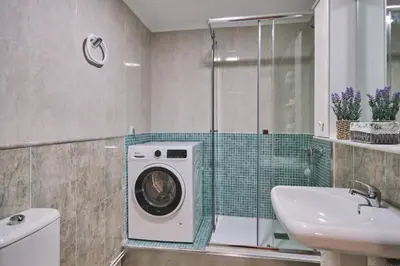a bathroom with a washing machine and a sink at Peregrina Pensión 5 in O Pedrouzo