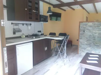 a kitchen with a counter and chairs in a room at Apartamentos rurales La Veiga in La Riera