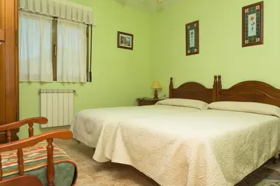a bedroom with a large bed and a chair at Apartamentos rurales La Veiga in La Riera