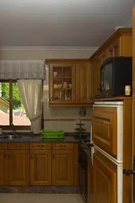a kitchen with wooden cabinets and a microwave and a television at Apartamentos rurales La Veiga in La Riera