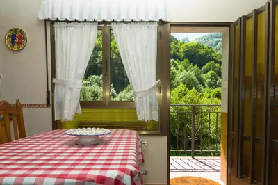 a table with a red and white checkered table cloth and a window at Apartamentos rurales La Veiga in La Riera