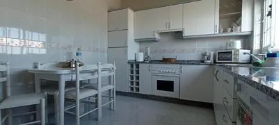 a kitchen with white cabinets and a sink and a table at Apartamento en las afueras in Ribadeo
