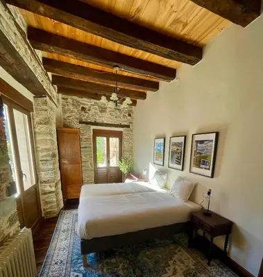 a bedroom with a large bed in a stone building at Casa El Colibrí in Villafranca del Bierzo