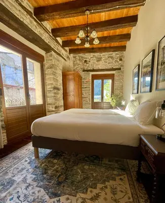 a bedroom with a large bed in a stone wall at Casa El Colibrí in Villafranca del Bierzo