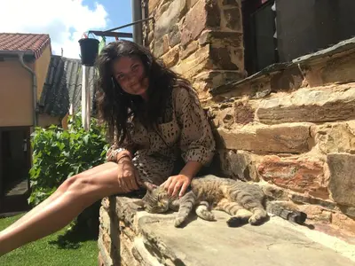 a woman petting a cat sitting on a wall at Albergue Gabino in El Ganso