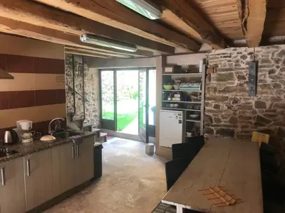 a kitchen with a table and a stone wall at Albergue Gabino in El Ganso