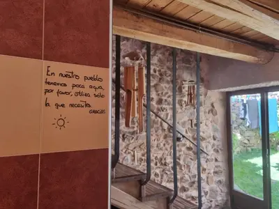 a room with a stone wall and a stair case at Albergue Gabino in El Ganso