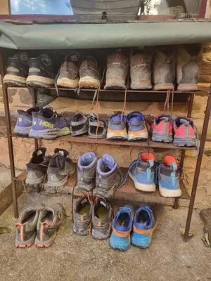a bunch of shoes on a shelf under a table at Albergue Gabino in El Ganso