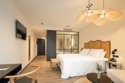 a bedroom with a white bed and a living room at Sercotel EsteOeste in Lugo
