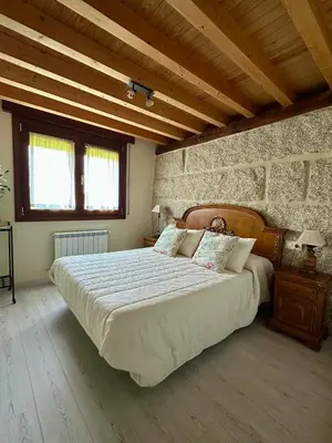 a bedroom with a large bed in a stone wall at Casa AsCampinas in Ourense