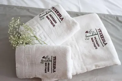 two white towels with flowers on a bed at PENSION BOUTIQUE TEIXEIRA, 3 ESTRELLAS in La Teijeira