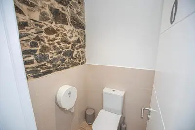 a bathroom with a toilet and a stone wall at Albergue A Fabrica in Santiago de Compostela