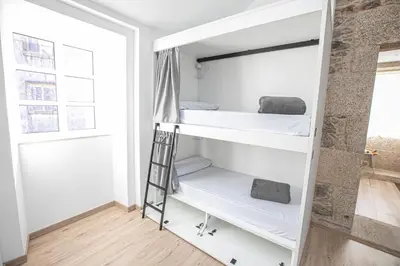 a room with two bunk beds and a ladder at Albergue A Fabrica in Santiago de Compostela