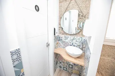 a bathroom with a mirror and a sink at Albergue A Fabrica in Santiago de Compostela