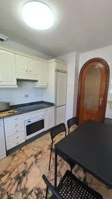 a kitchen with white cabinets and a table with chairs at Montirón Lucus Confort in Lugo