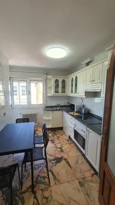 a kitchen with white cabinets and a table and chairs at Montirón Lucus Confort in Lugo