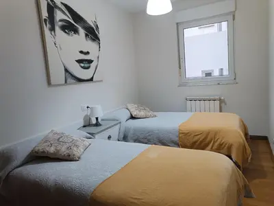 a bedroom with two beds and a picture of a woman at Recanto Milladoiro in Milladoiro