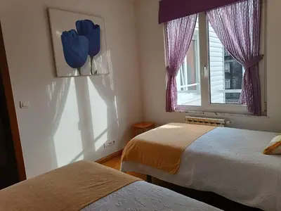 a bedroom with two beds and a window with purple curtains at Recanto Milladoiro in Milladoiro