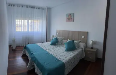 a bedroom with a bed with blue pillows and a window at Viviendas vacacionales as lagas in Palas de Rei