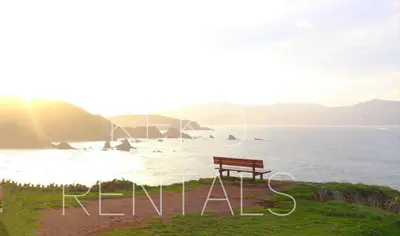 a bench sitting on the side of a body of water at Penthouse Panorámico in Viveiro