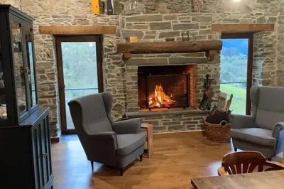 a living room with a stone fireplace and two chairs at Casona Rural de Lujo con increíbles vistas, La Casa de Rafael, ahora con 4 habitaciones in San Antolín